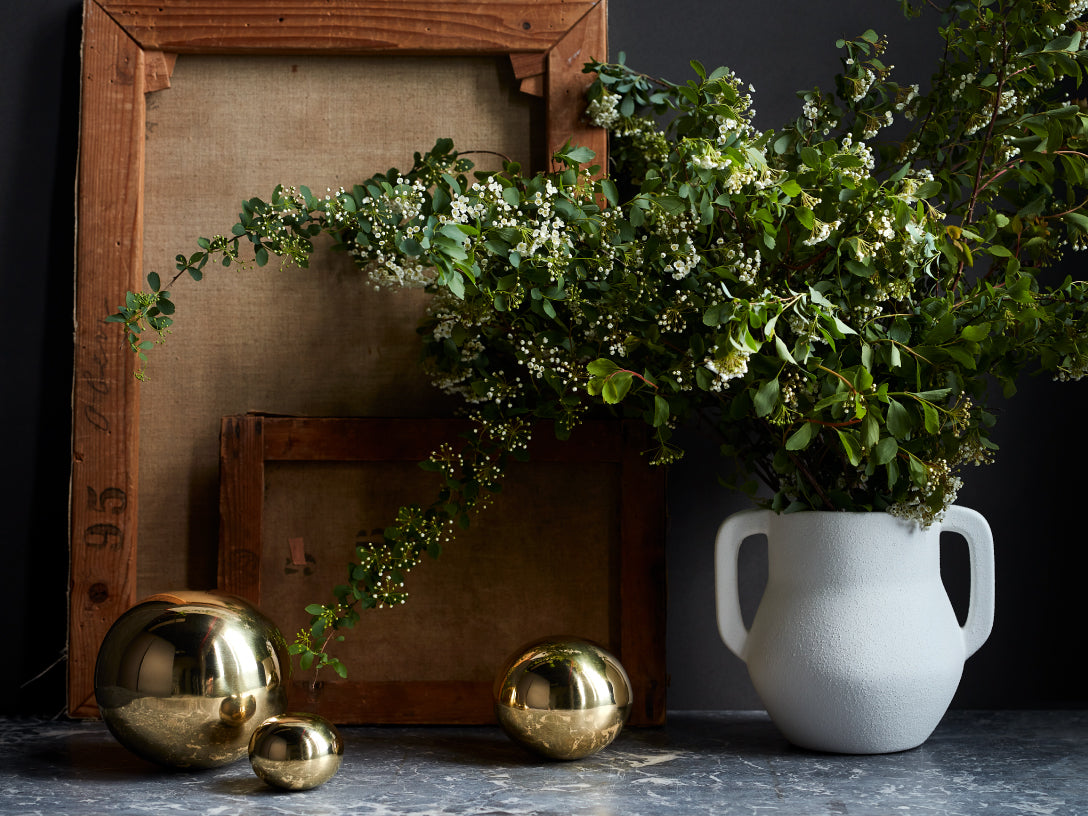 white vase with greens and gold orbs